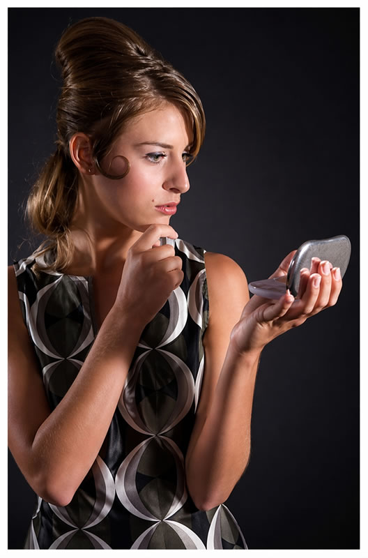 a lovely young woman from the 60's looking into a compact mirror