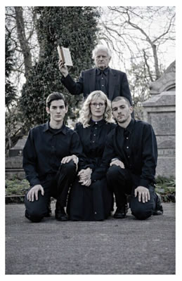 four people wearing black in a graveyard